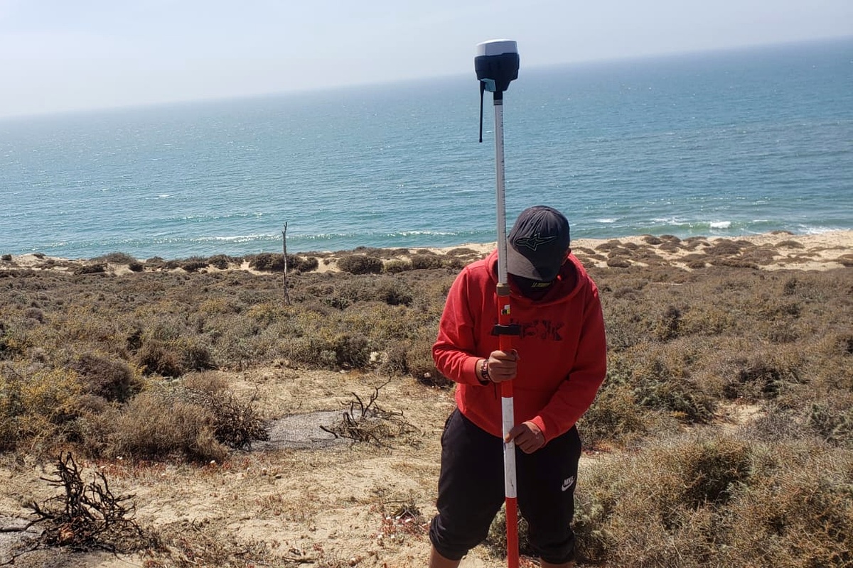 Surveyor collecting data with a GNSS rover on a coastal property