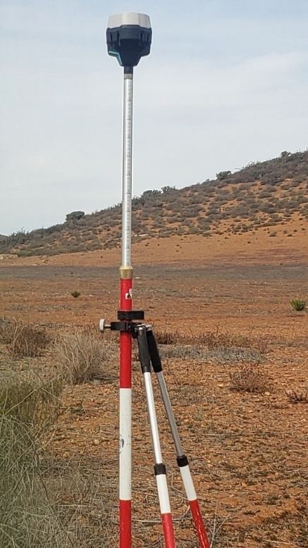 Equipo GNSS montado en tripié sobre terreno rústico